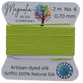 Lime green thread on a card with 'Magnolia Bead Company' branding against a wooden background